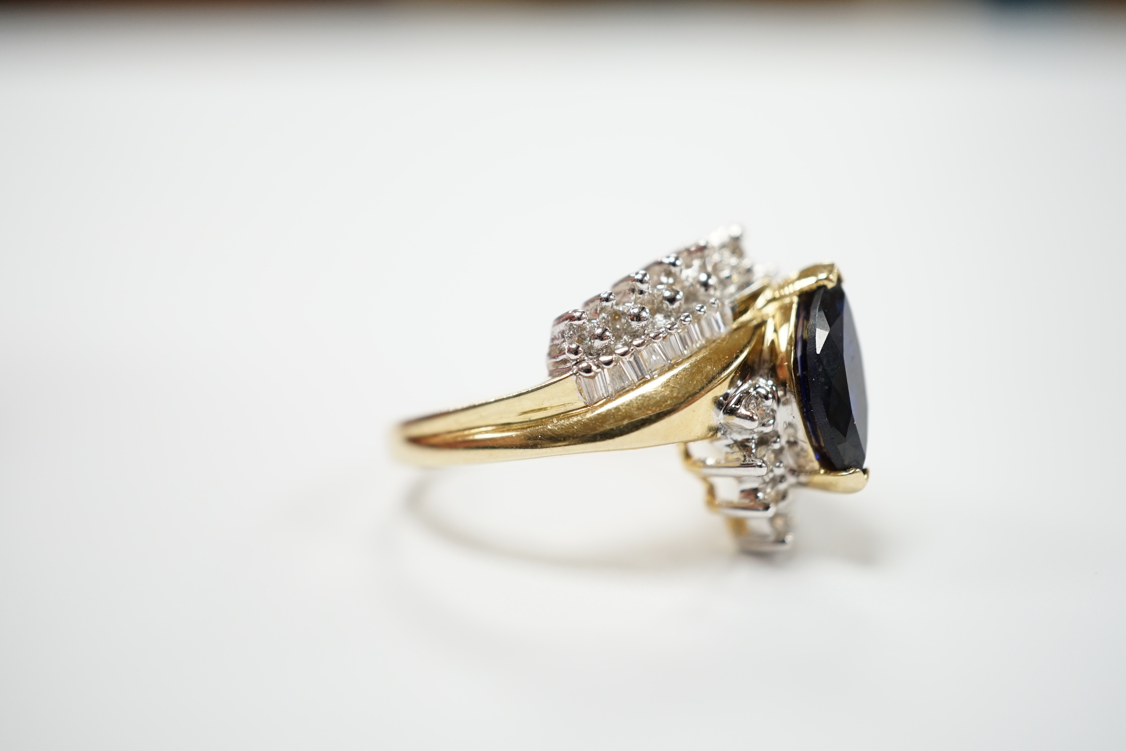 A modern 14k and single stone marquise cut sapphire and diamond chip cluster set crossover dress ring, size M, gross weight 5.3 grams.